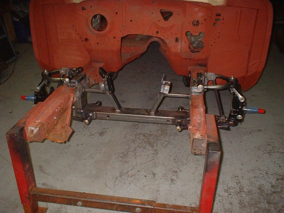 Car chassis frame with front suspension components installed, mounted on a red stand