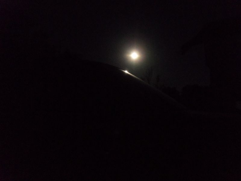 Night shot along a dark car body panel with the moon overhead