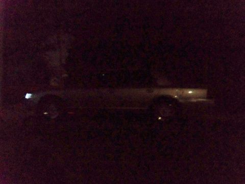 2000 Mercury Grand Marquis - A dark photo shows a sedan parked at night with its headlights illuminated.