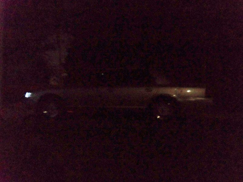 Side view of a sedan at night, headlights on