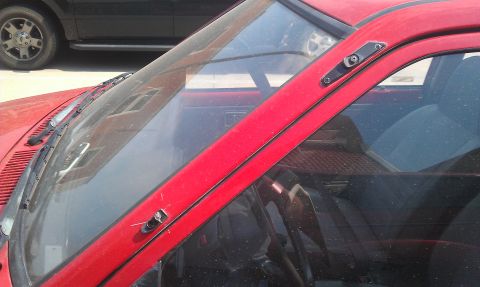 1991 Ford Festiva - Close-up of a red car's interior, showing the windshield and dashboard area, with another vehicle visible behind it.