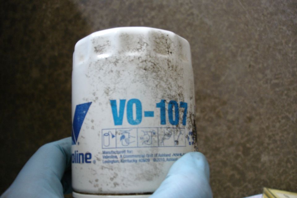 Hand holding a Valvoline VO-107 oil filter. Filter has some dirt on it