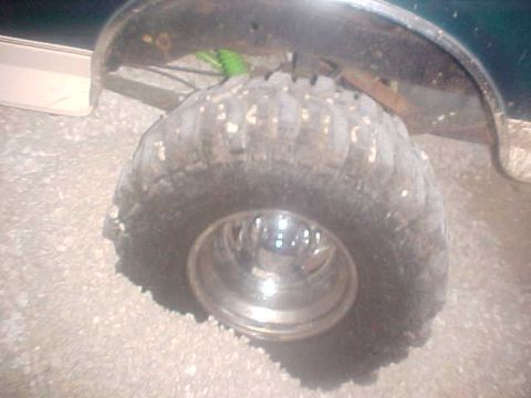 1996 Ford Bronco - A close-up view of a large, aggressive off-road tire and its shiny chrome wheel. The vehicle's fender is visible overhead.