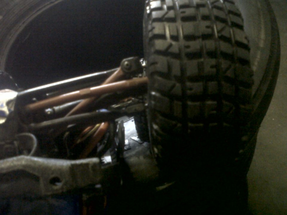 Close-up of an off-road tire and suspension parts, with 'SUPERMOTORS' logo visible