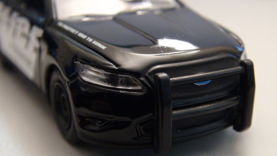 Black police car with push bar and "to protect and to serve" text on hood