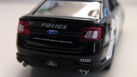 1993 Ford Taurus - Rear view of a black Ford Police Interceptor with police markings and website address on the trunk.