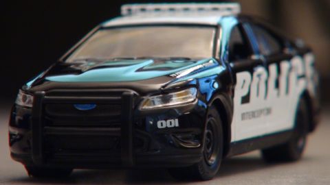 1993 Ford Taurus - Toy police car model with 'POLICE INTERCEPTOR' text and unit number 001.