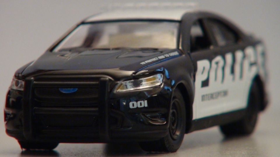 Black and white police car with "POLICE INTERCEPTOR" text, front grille, and push bar