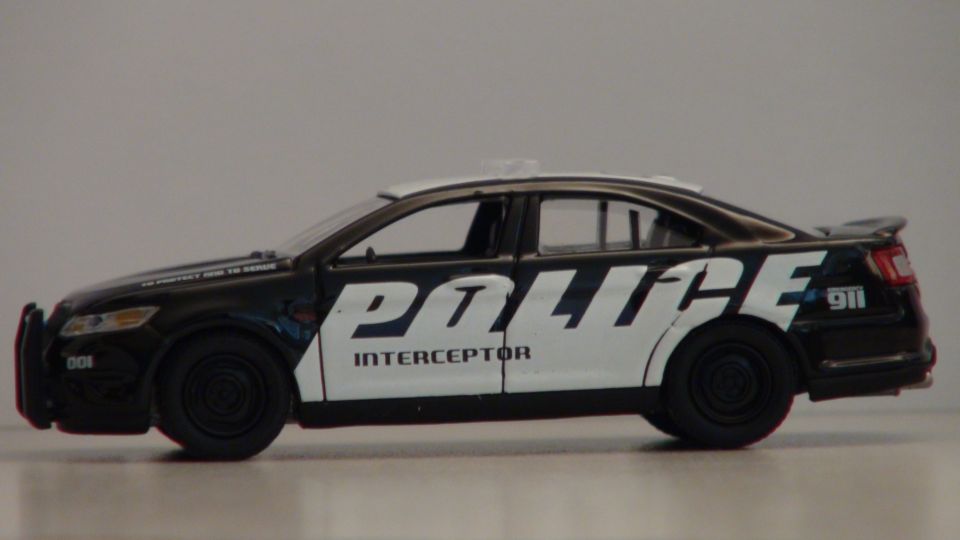 Black and white toy police car with 'POLICE INTERCEPTOR' text on the side
