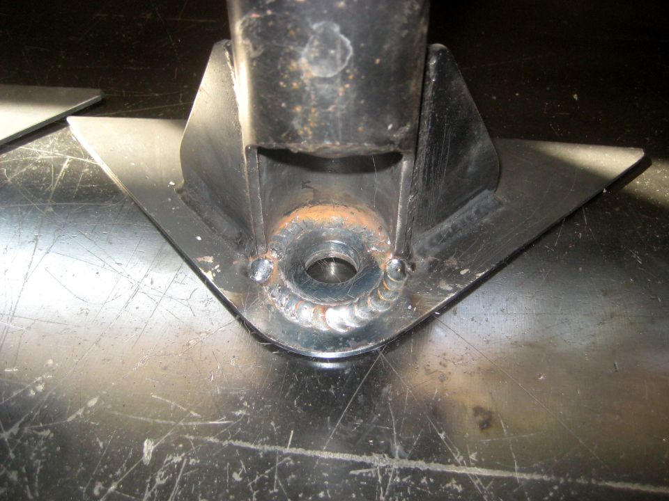 Close-up of a custom metal bracket with welds, likely for a skid plate, on a workbench