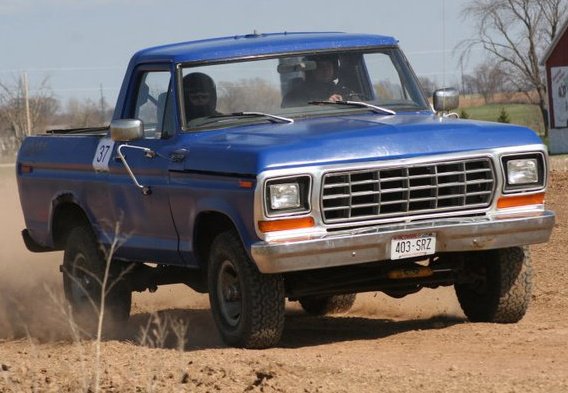 Blue pickup truck with number 37 on door, driving on dirt road