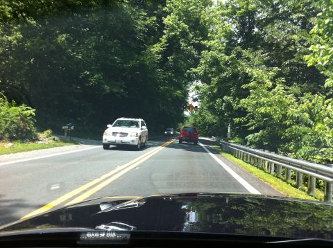 1999 Ford Crown Victoria - Driving on a tree-lined road with other vehicles ahead.
