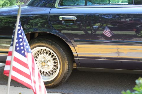 1999 Ford Crown Victoria - Side view of a 1999 Ford Crown Victoria, an American flag and reflections on the dark paint.