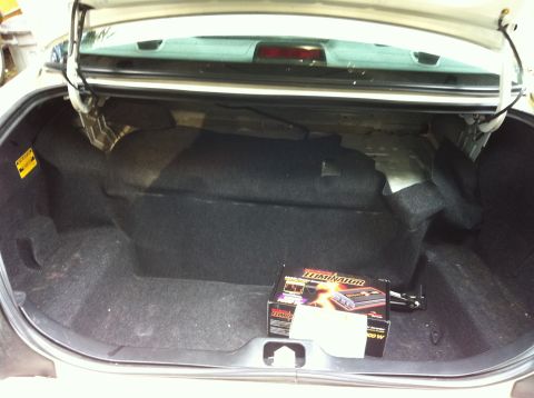 2005 Ford Crown Victoria - The trunk of a 2005 Ford Crown Victoria contains a subwoofer box and an amplifier, with the trunk lid open.