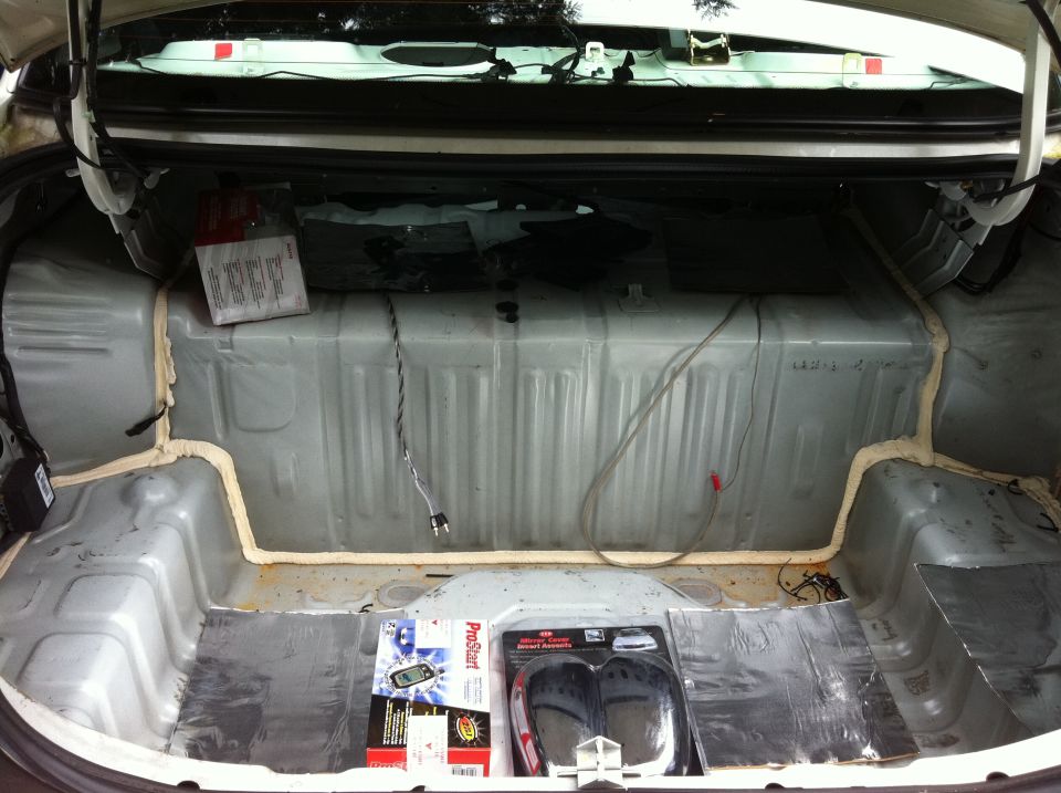 Open car trunk with stripped interior and a sound-deadening project underway