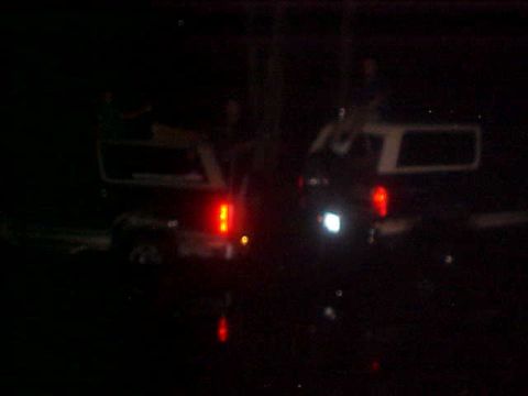 1996 Ford Bronco - Two SUVs are visible at night, with one displaying illuminated brake lights.