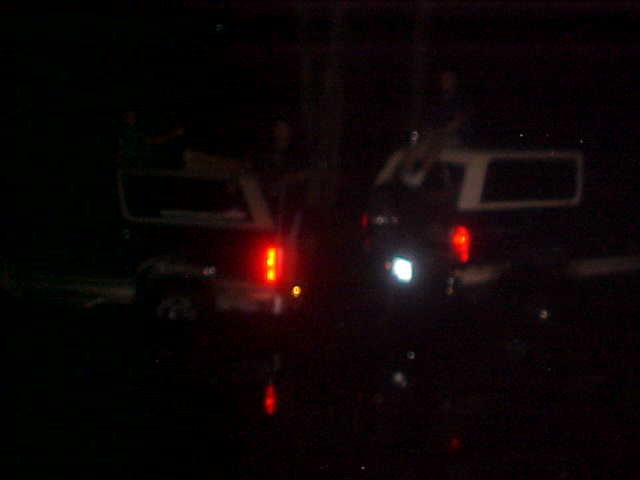 Two SUVs parked at night, one with its brake lights on