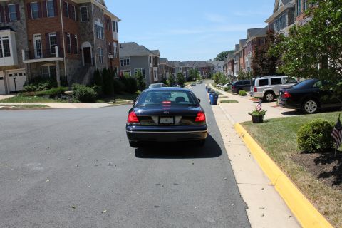 1999 Ford Crown Victoria - Dark blue Ford Crown Victoria is parked on a residential street, with other vehicles and townhouses visible.