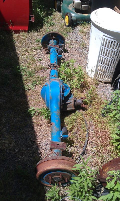 1992 Ford Ranger - A blue rear axle assembly with drum brakes sits on the ground outdoors.