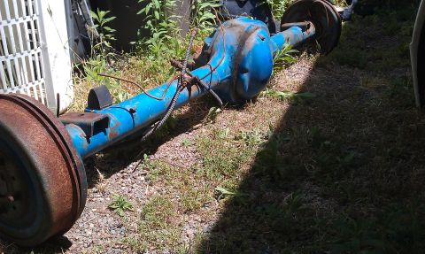 1992 Ford Ranger - A blue rear axle assembly with drum brakes is shown outdoors, resting on grass and gravel.