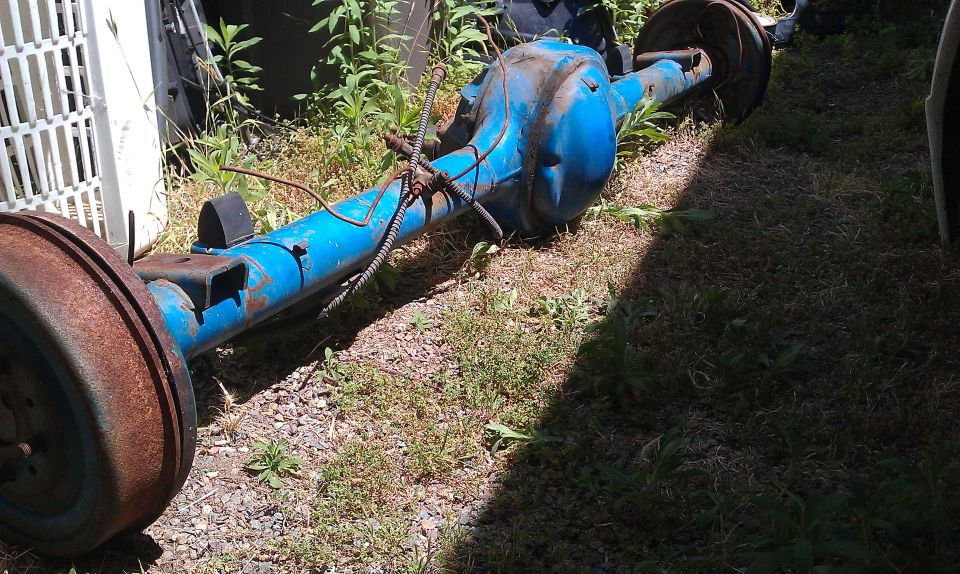 blue rear axle assembly with drum brakes, sitting on the ground