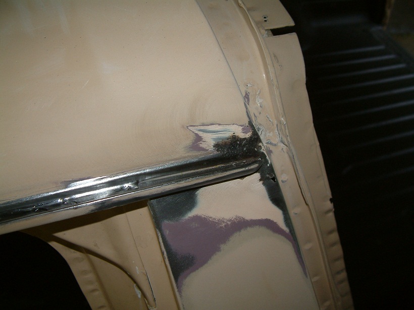 Close-up of vehicle body panel with primer and metal work visible