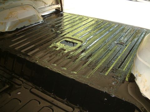1983 Ford Bronco - The interior cargo area of a 1983 Ford Bronco shows a freshly applied black protective coating over its ribbed floor.