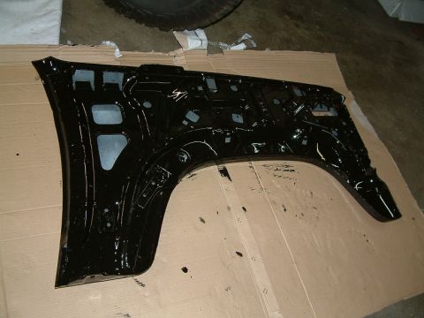1983 Ford Bronco - Inner structure of a black fender is displayed on a cardboard surface, with a tire visible in the background.