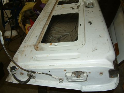 1983 Ford Bronco - This is a white tailgate with two window openings, exhibiting rust and wear.