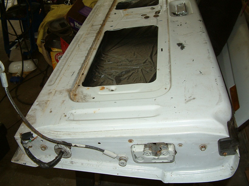 White tailgate with two window openings, showing rust and wear