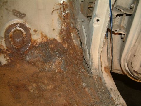 1983 Ford Bronco - Close-up of heavily rusted metal, likely a vehicle's undercarriage or door jamb.