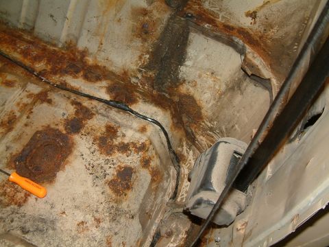 1983 Ford Bronco - Undercarriage of a vehicle showing significant rust and exposed wiring.