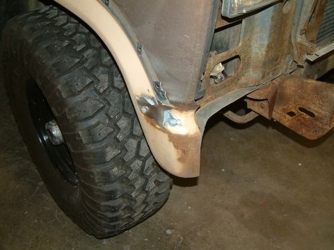 1983 Ford Bronco - This close-up shows the front fender and tire of a vehicle, with visible rust and repair work on the metal.
