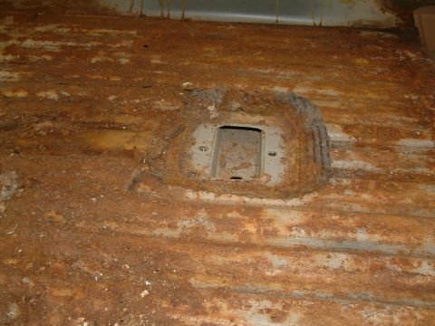 1983 Ford Bronco - The interior floor pan shows extensive rust and corrosion, obscuring any specific vehicle details.