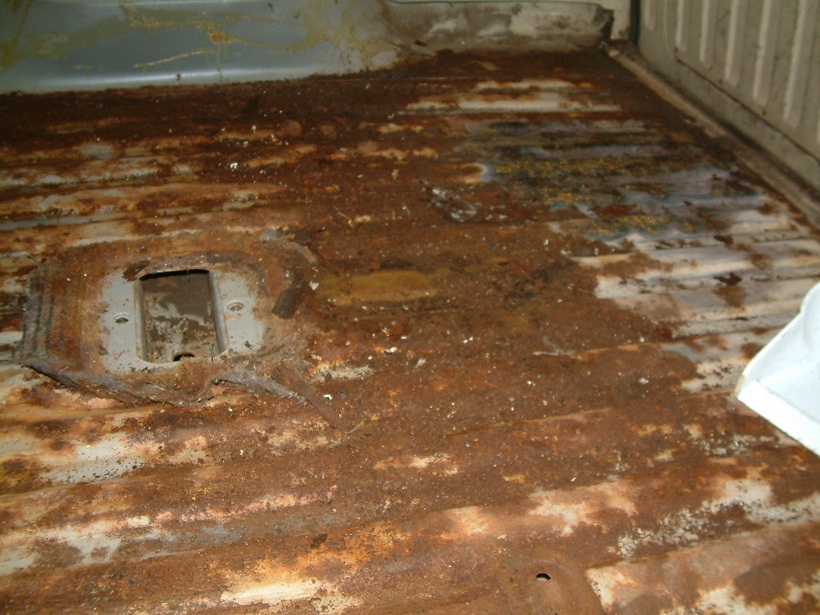 rusted out floor of a vehicle, looks like a truck bed or cargo area