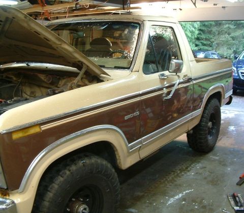 1983 Ford Bronco - A two-tone brown and tan 1983 Ford Bronco is shown with its hood up in a garage.