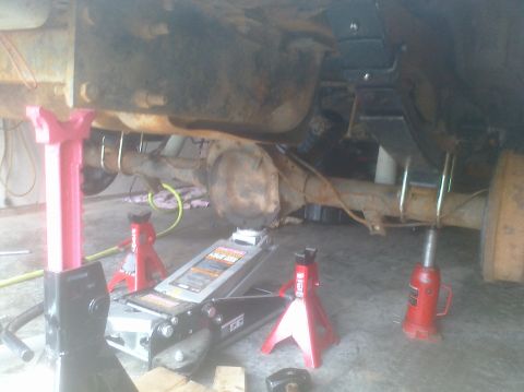 1995 Ford Bronco - Vehicle's rear axle and suspension components are supported by jack stands and a floor jack during maintenance.