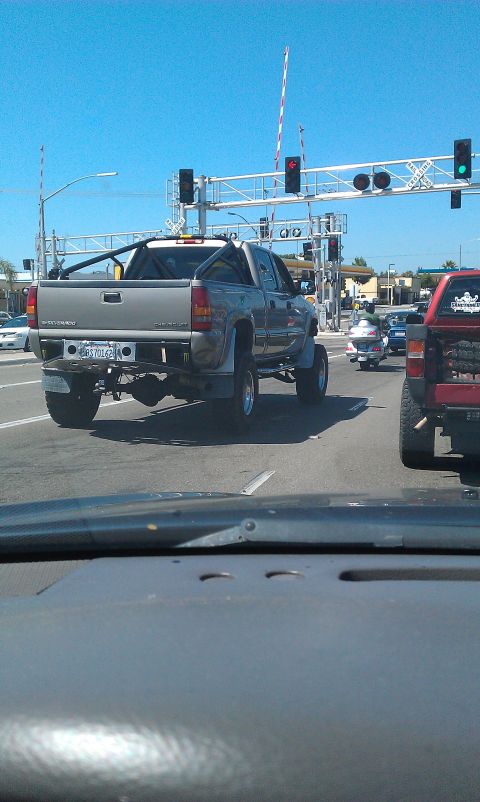 1992 Ford Ranger - A lifted silver pickup truck waits at a railroad crossing with traffic behind it.
