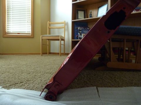 1997 Dodge 2500 - Red car part on floor, with a chair and bookshelf in the background.