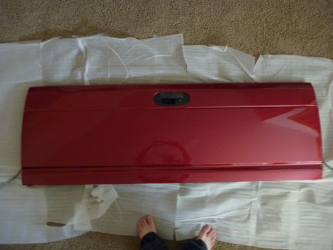 1997 Dodge 2500 - A red pickup truck tailgate is laid out on protective wrapping on a carpeted floor.