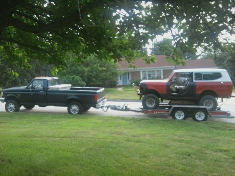 1978 International Scout II - A red and white International Scout II is transported on a U-Haul trailer, towed by a dark blue pickup truck.