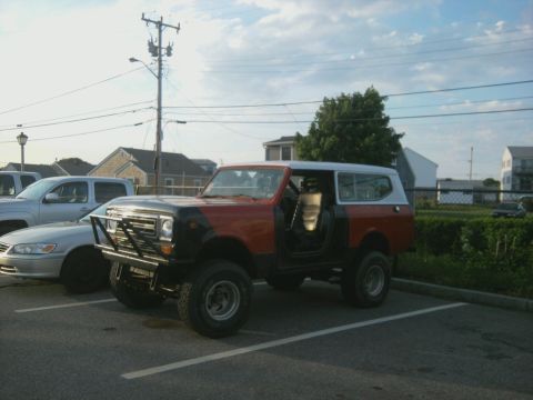 1978 International Scout II - A red and black 1978 International Scout II is parked in a lot next to another vehicle.
