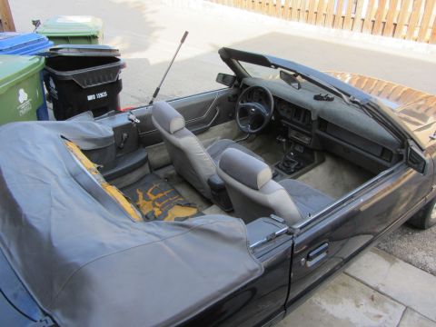 1985 Ford Mustang - Interior view of a 1985 Ford Mustang convertible with worn seats and a visible dashboard.