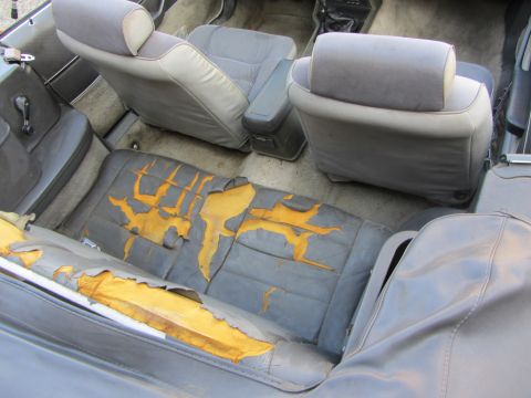 1985 Ford Mustang - The interior of a car shows significant wear and tear on the seats, with exposed foam visible.