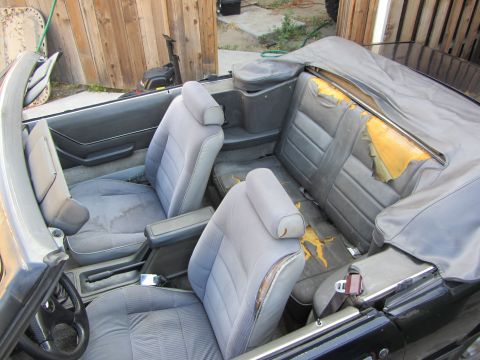 1985 Ford Mustang - Interior view of a 1985 Ford Mustang convertible with worn seats and a soft top.