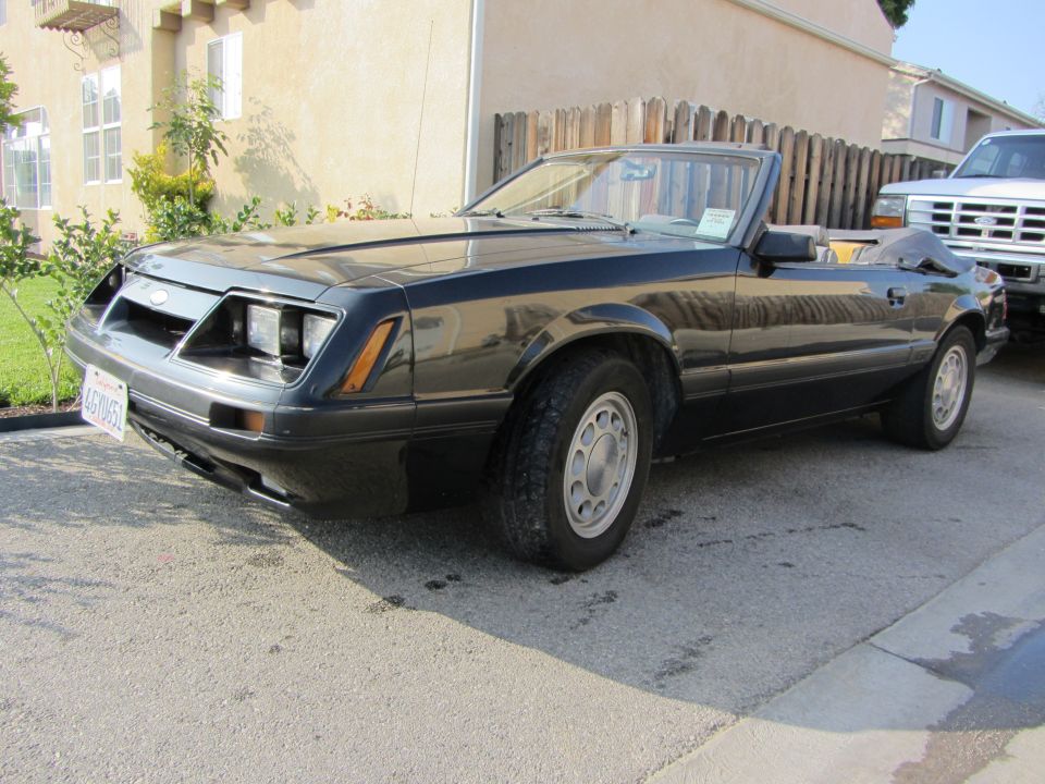 Black Fox-body Mustang LX convertible with top down and for-sale sign, front 3/4 view