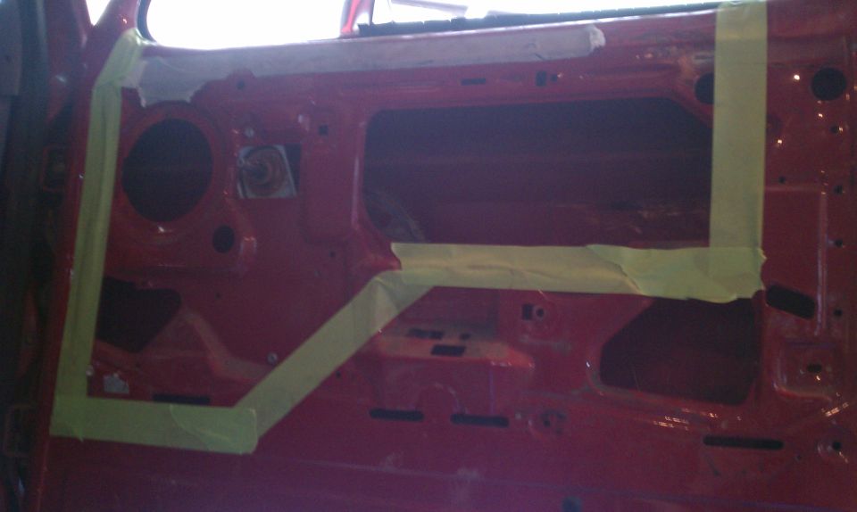 Red car door interior with masking tape applied to prepare for painting