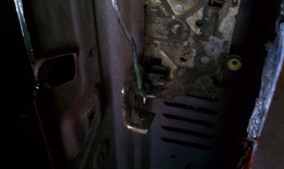 Close-up of a vehicle's interior door latch mechanism, showing the metal components and wiring