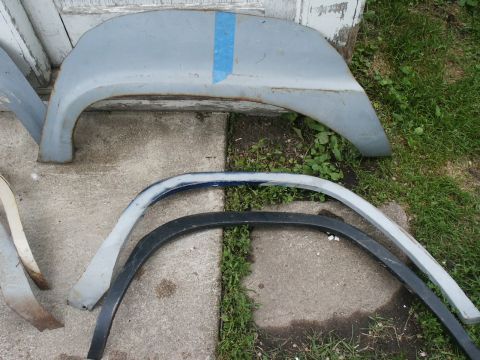 1966 Ford Bronco - Several fender flares, one with blue tape, lie on concrete and grass.