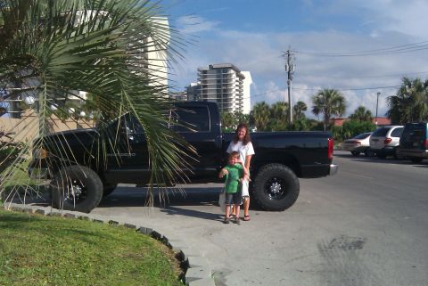 1967 Ford Mustang - A black pickup truck is parked outside with two people standing beside it.